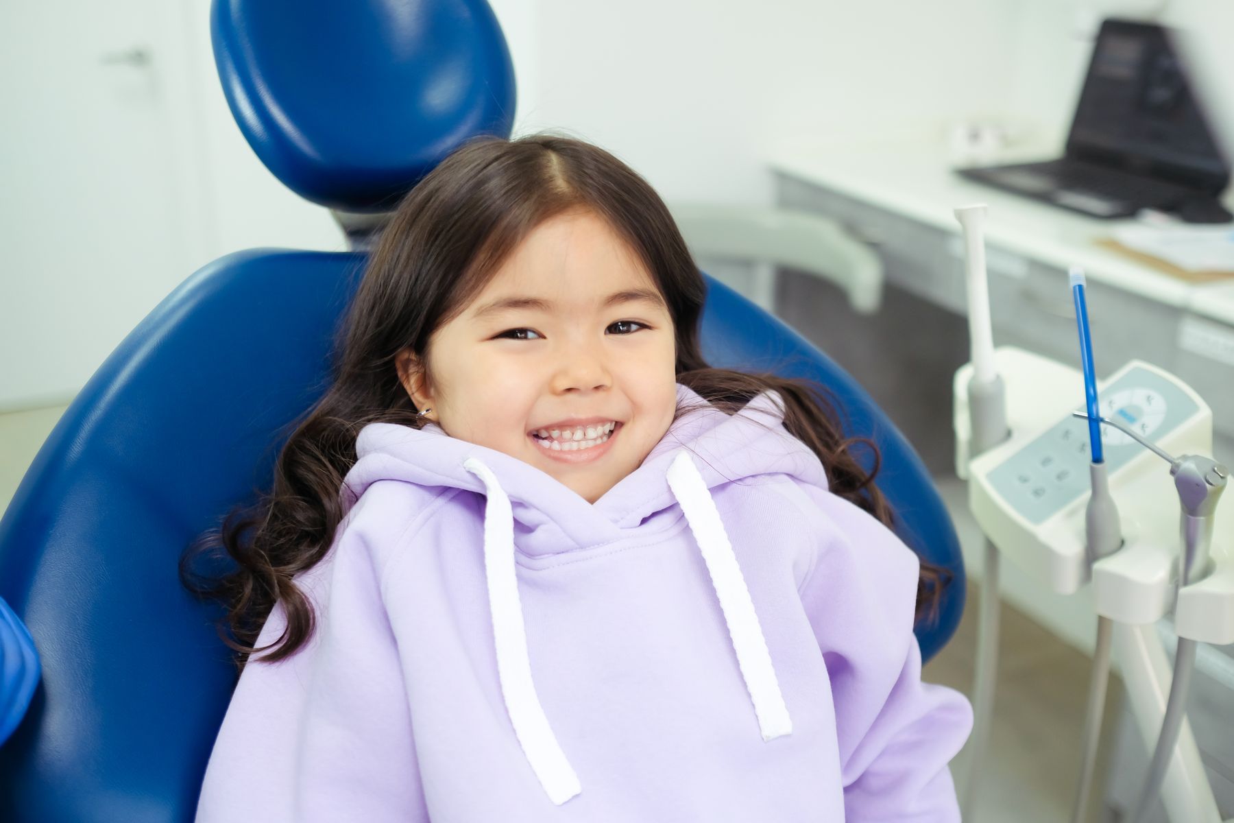 Vajzë duke buzëqeshur në karrigen dentare gjatë kontrollit